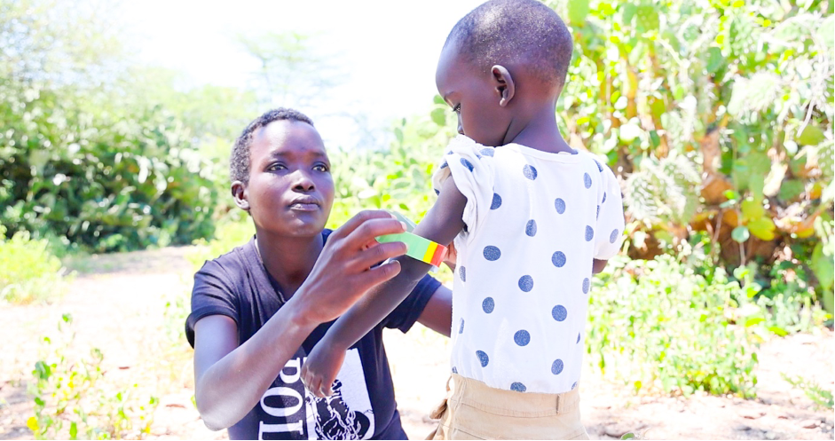 Marion screens her daughter for malnutrition. MUAC tape is a tool used to measure the circumference of a child’s mid-upper arm, and identify whether a child may be malnourished. If the score indicates red or yellow, then the child is admitted to out-patient therapeutic or supplementary feeding program for treatment.