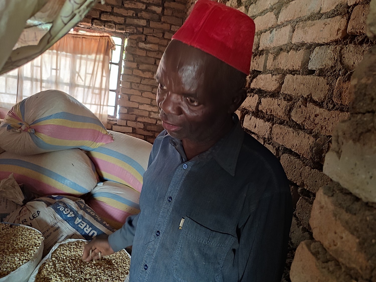 M'baya, a member of the Chemba Fish Farming Cooperative showing bags of maize he bought for his family after selling fish.