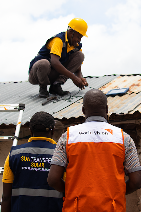 World Vision and Solartransfer staff putting a solar panel charger on the roof of a house so it can get power from the sun in Kenya's Isiolo County. ©World Vision Photo/Wesley Koskei