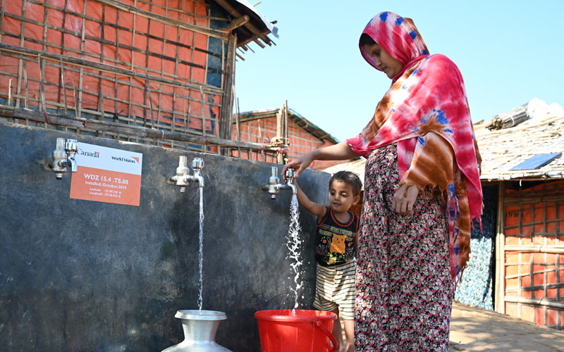 Rohingya child and mum getting water from piped supply