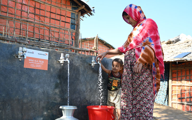 Rohingya child and mum getting water from piped supply