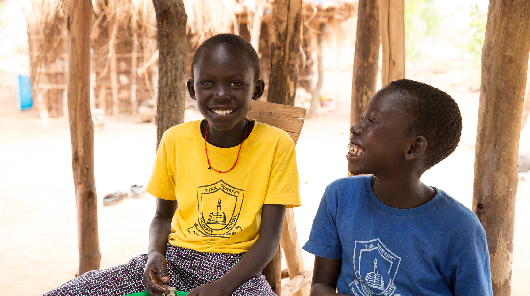 Two child refugees smiling and eating