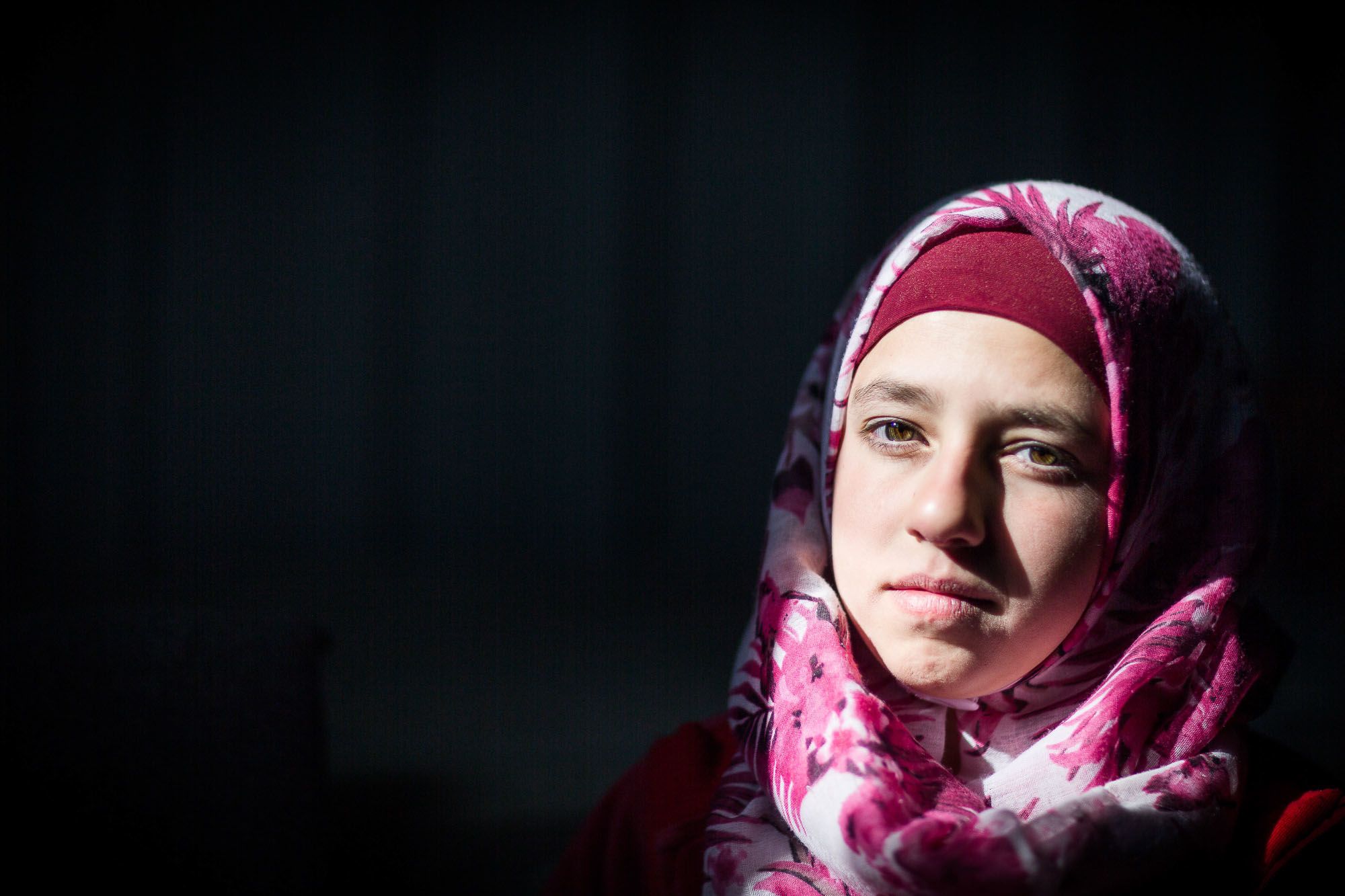 Girl in dark room, looking sad into distance.