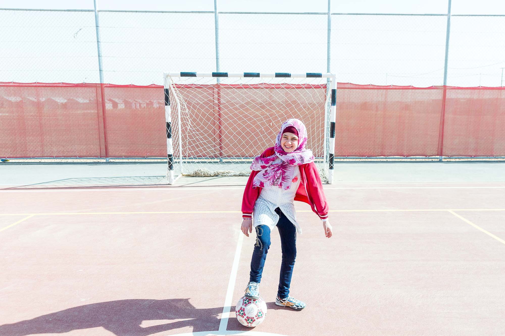 Girl playing with ball, smiling.