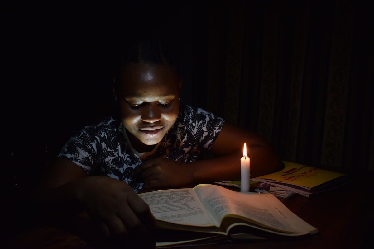 Halima studies by candlelight at night as she has no electricity in her home. 