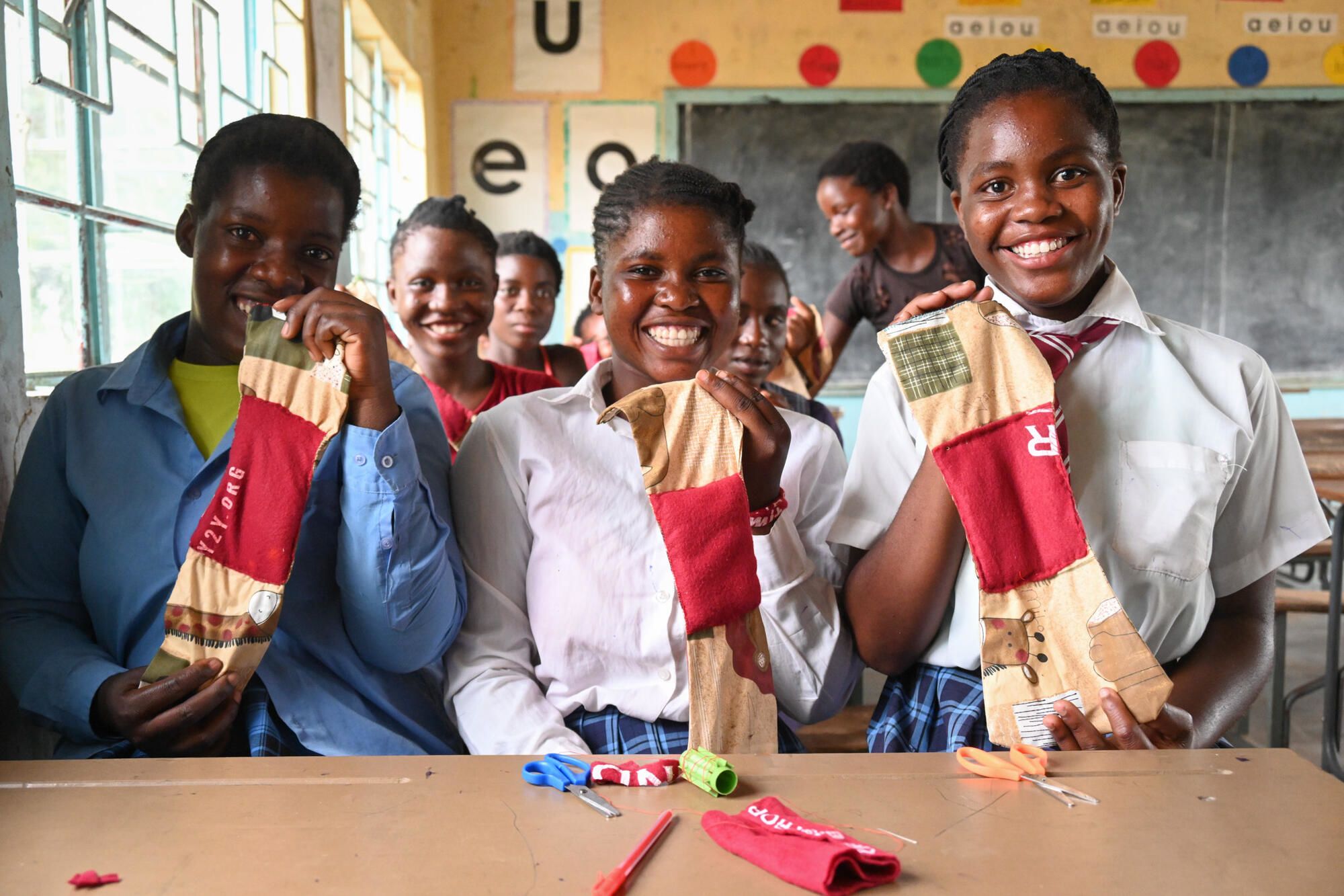 Girls hold up reusable feminine hygience products at school