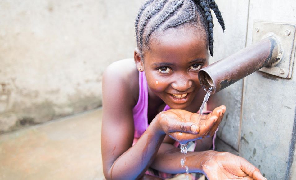 Insta, a 12 year old sponsored child from Sierra Leone drinks clean water from a well.