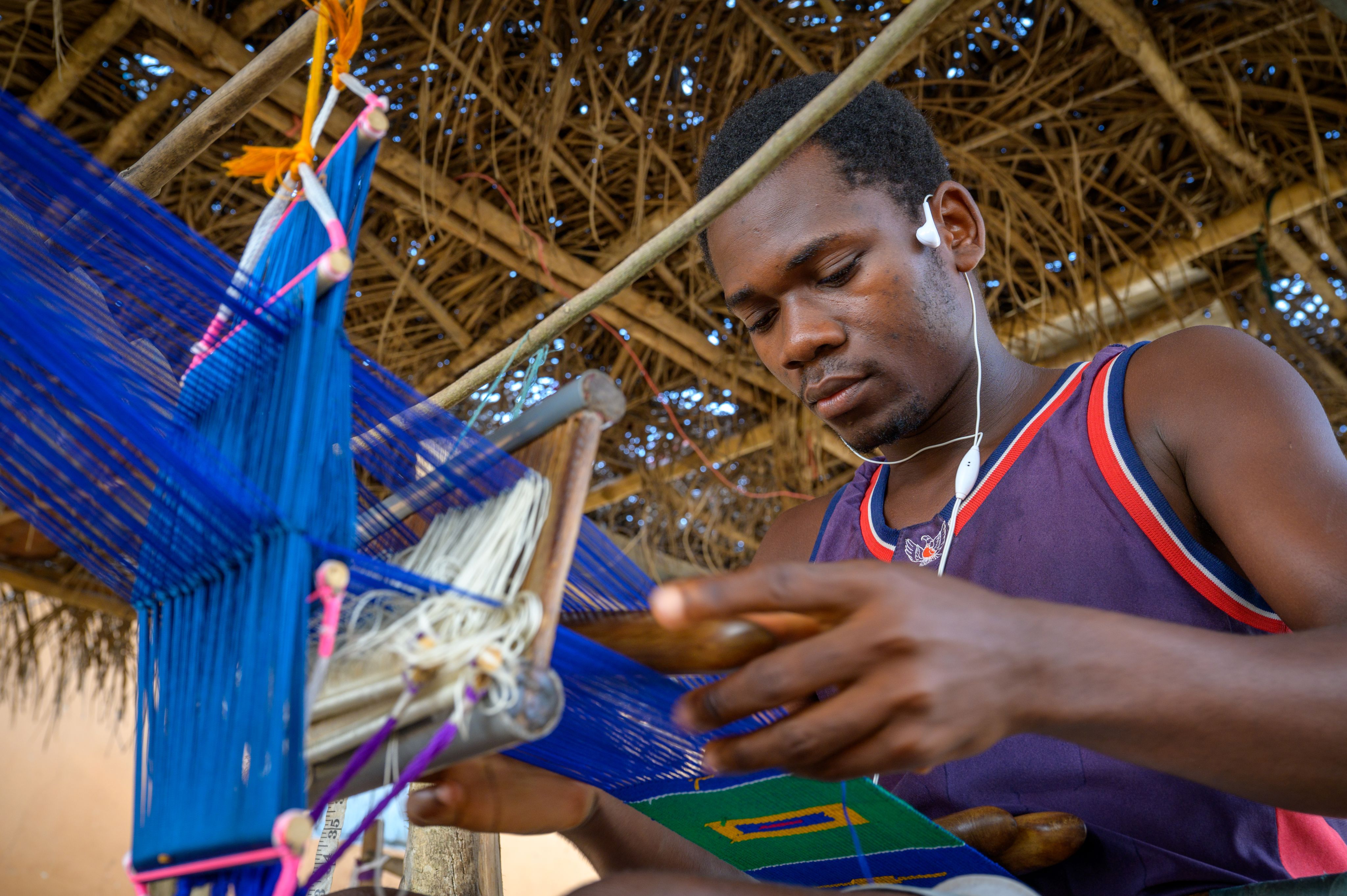 A young artisan in Ghana weaves textiles.