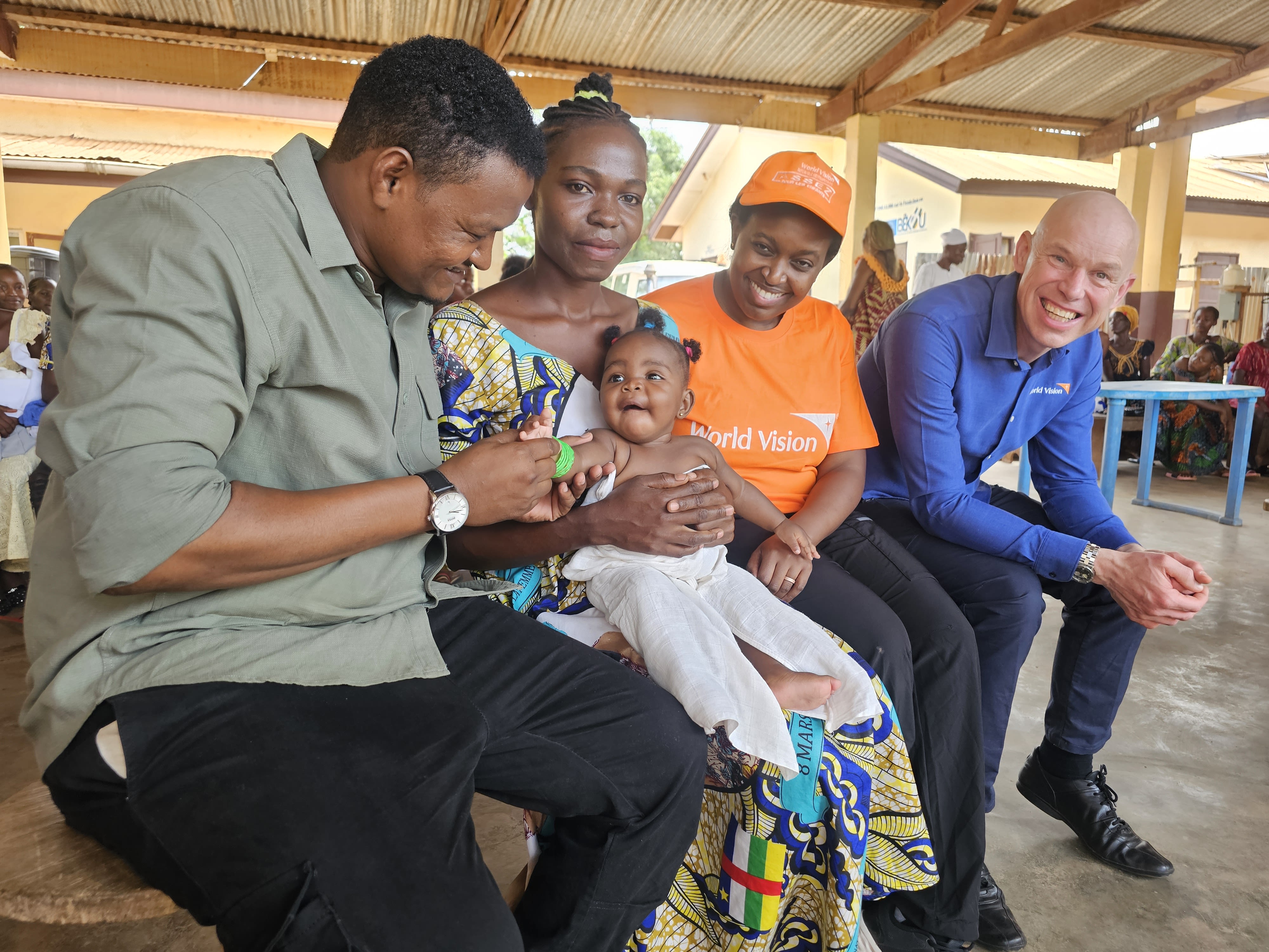 Andrew Morley sits with a World Vision staff and parents with their baby