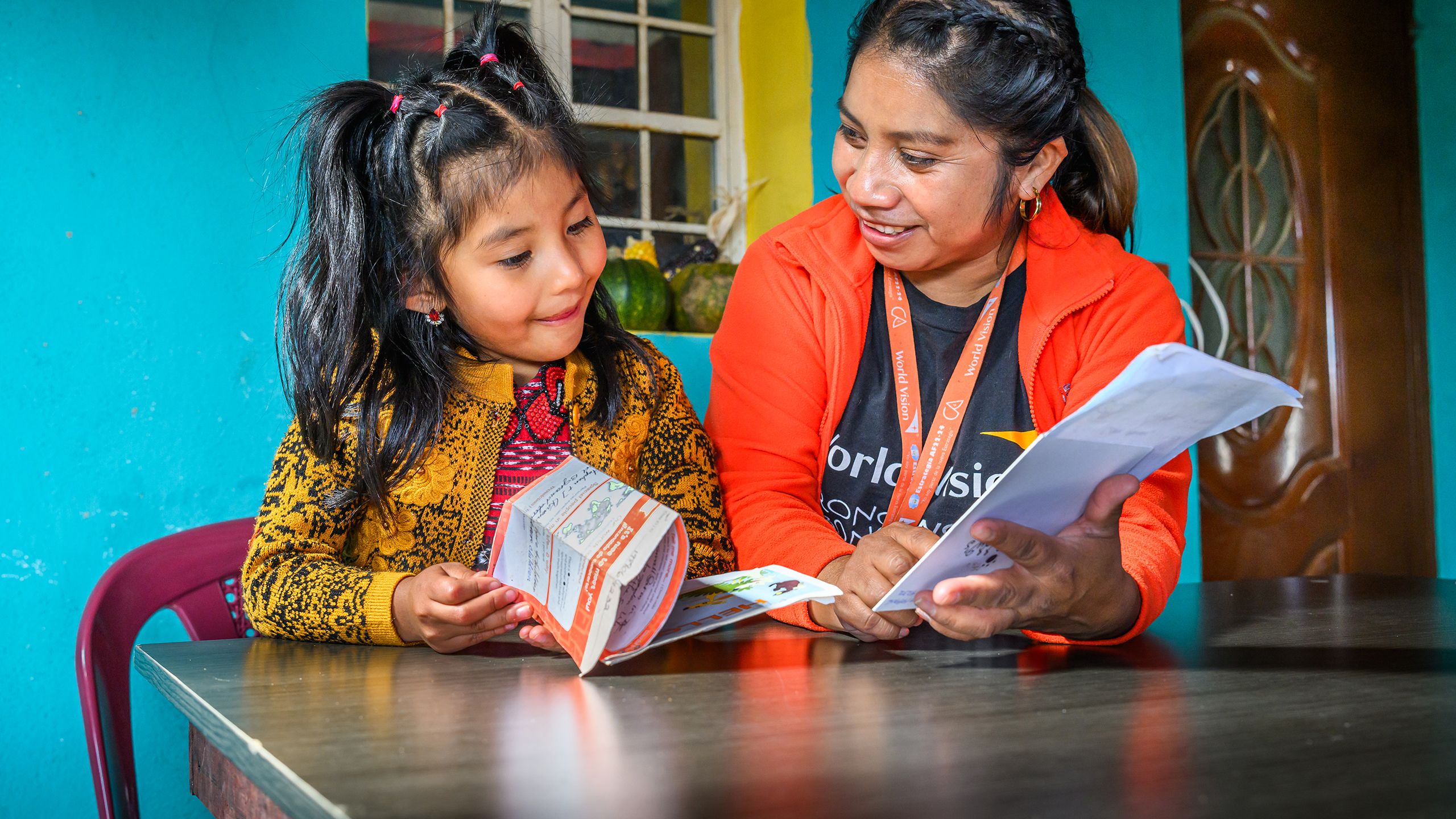 World Vision Staff sits with a young girl looking at a paper