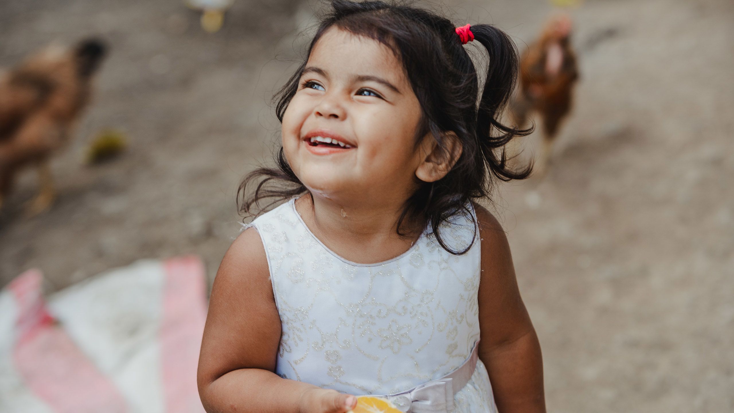 Girl in a white dress looks up smiling