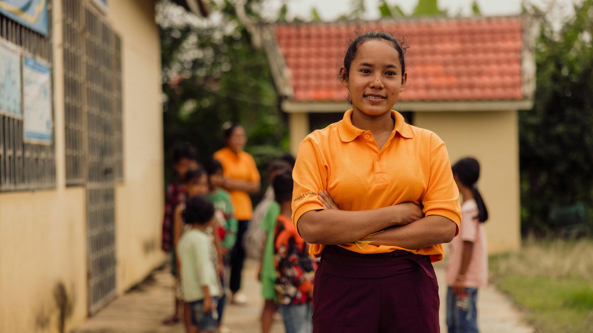 A girl stands strongly with arms crossed while standing in front of a children's group