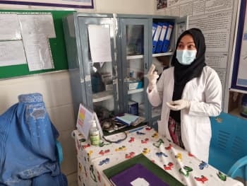 A masked female healthcare professional in her surgery.