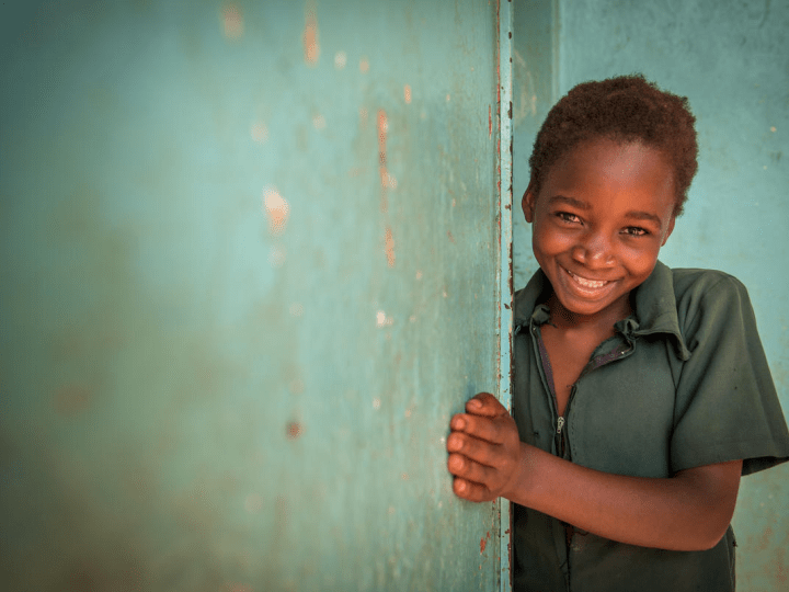 Girl smiling next to green wall