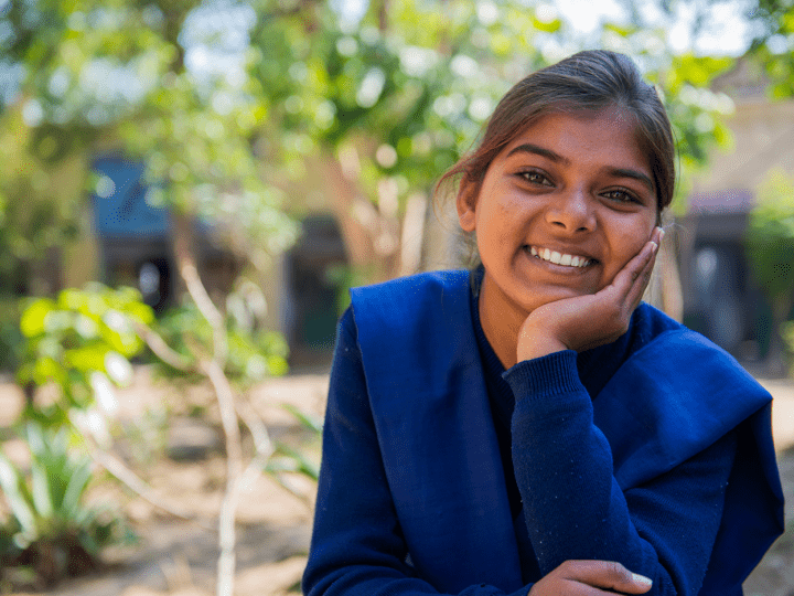 Smiling girl in blue dress resting her head on her hand