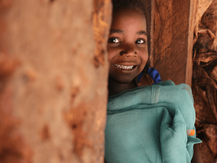 Girl smiling from behind a wall