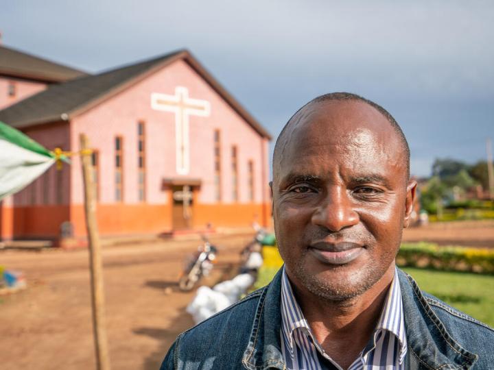 Church leader stands in front of church in the democratic republic of congo