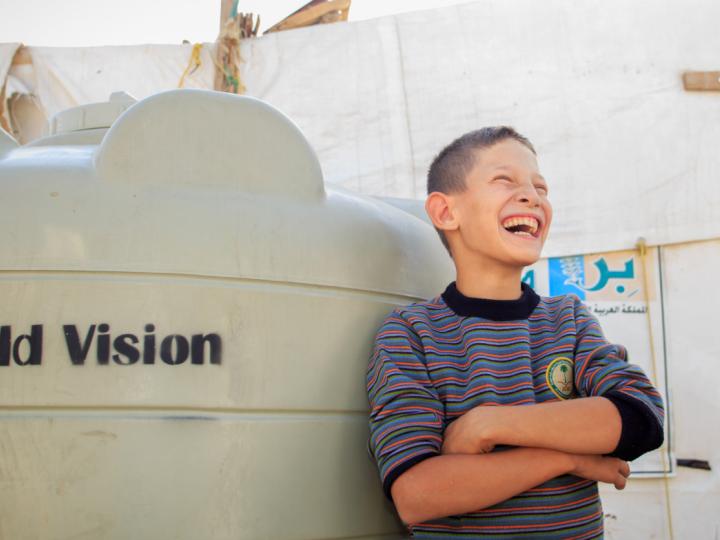 Boy smiling, leaning against water tank