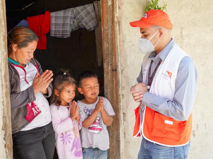 World Vision staff member prays with child in Ecuador