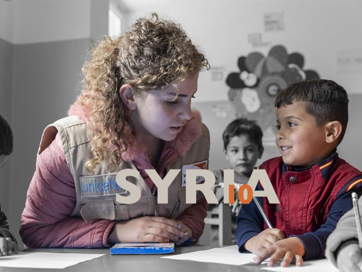Syria_10 banner_World Vision staff member helps Syrian refugee child in camp in Jordan