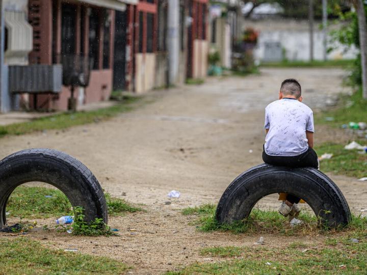 Child sits alone on a tire stuck in the ground
