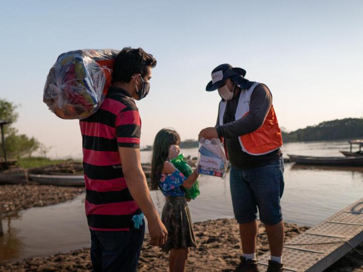 WVI staff gives bags of food to adult man and female child