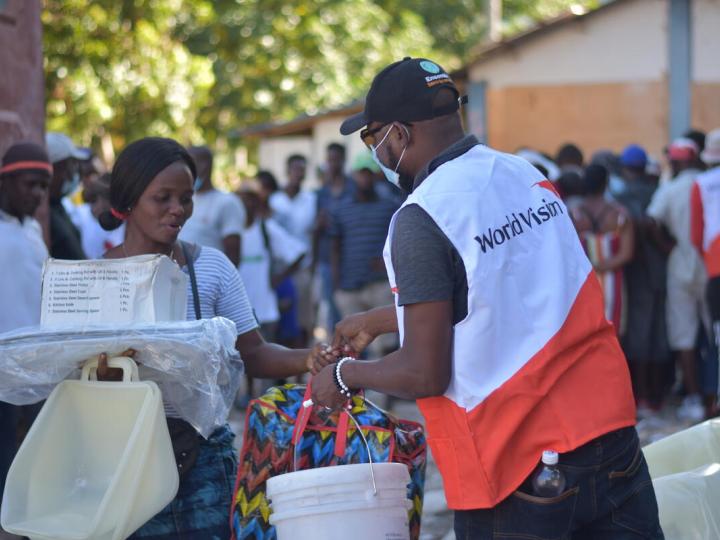 World Vision staff gives food to a woman