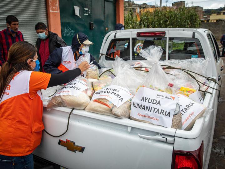 woman distributes packages of food from the bed of a truck