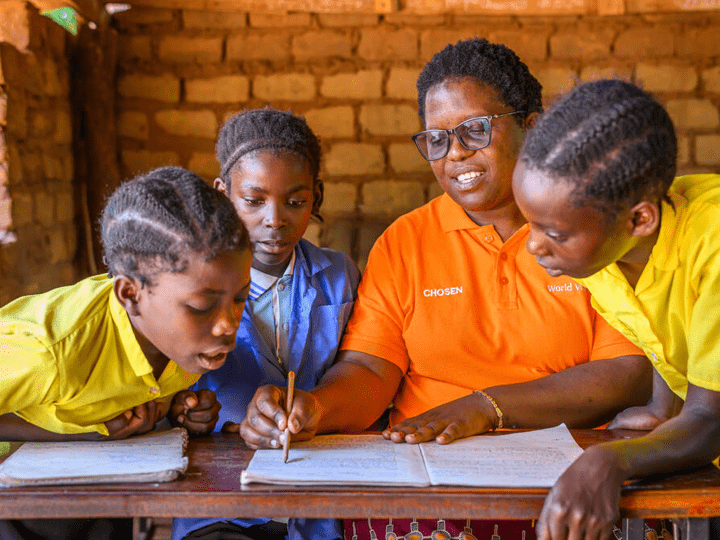 World Vision Zambia staff member Mulambwa Sikopo, Manyinga ADP manager, sits with children in a Manyinga school in Zambia.