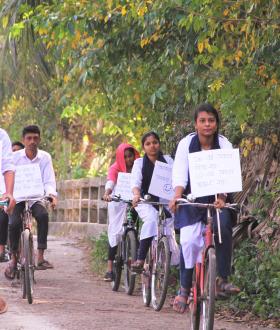 a group of adolescents cycling with advocacy messages