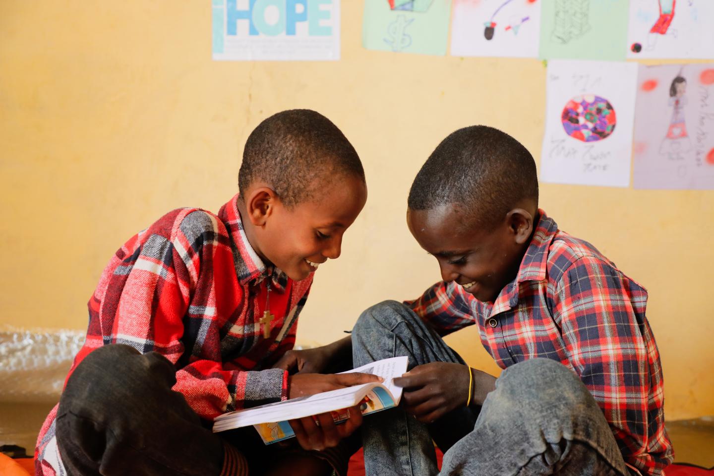 Bereket reading a book with his friend smiling