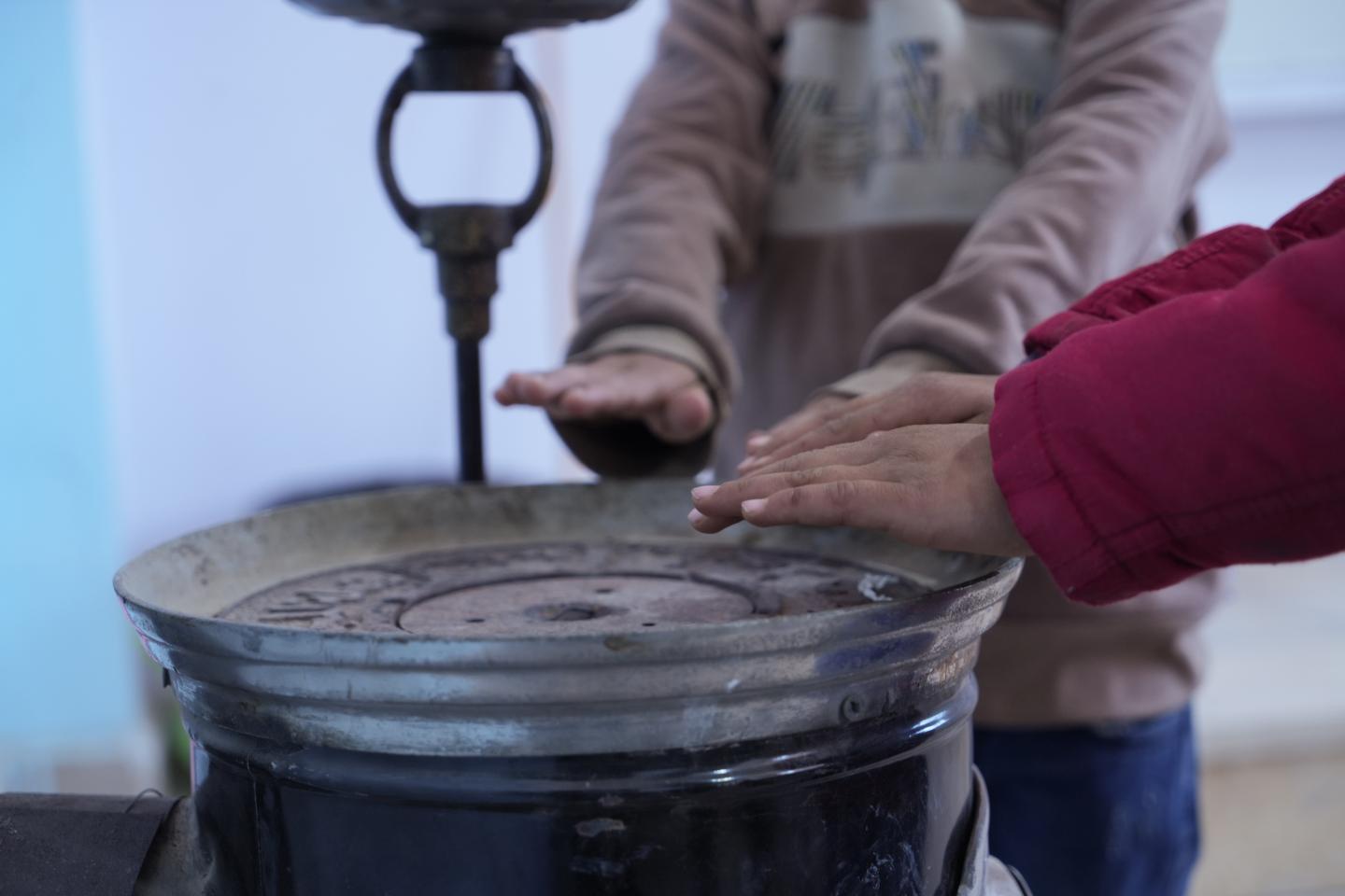 Children using the heater in class during the cold winter