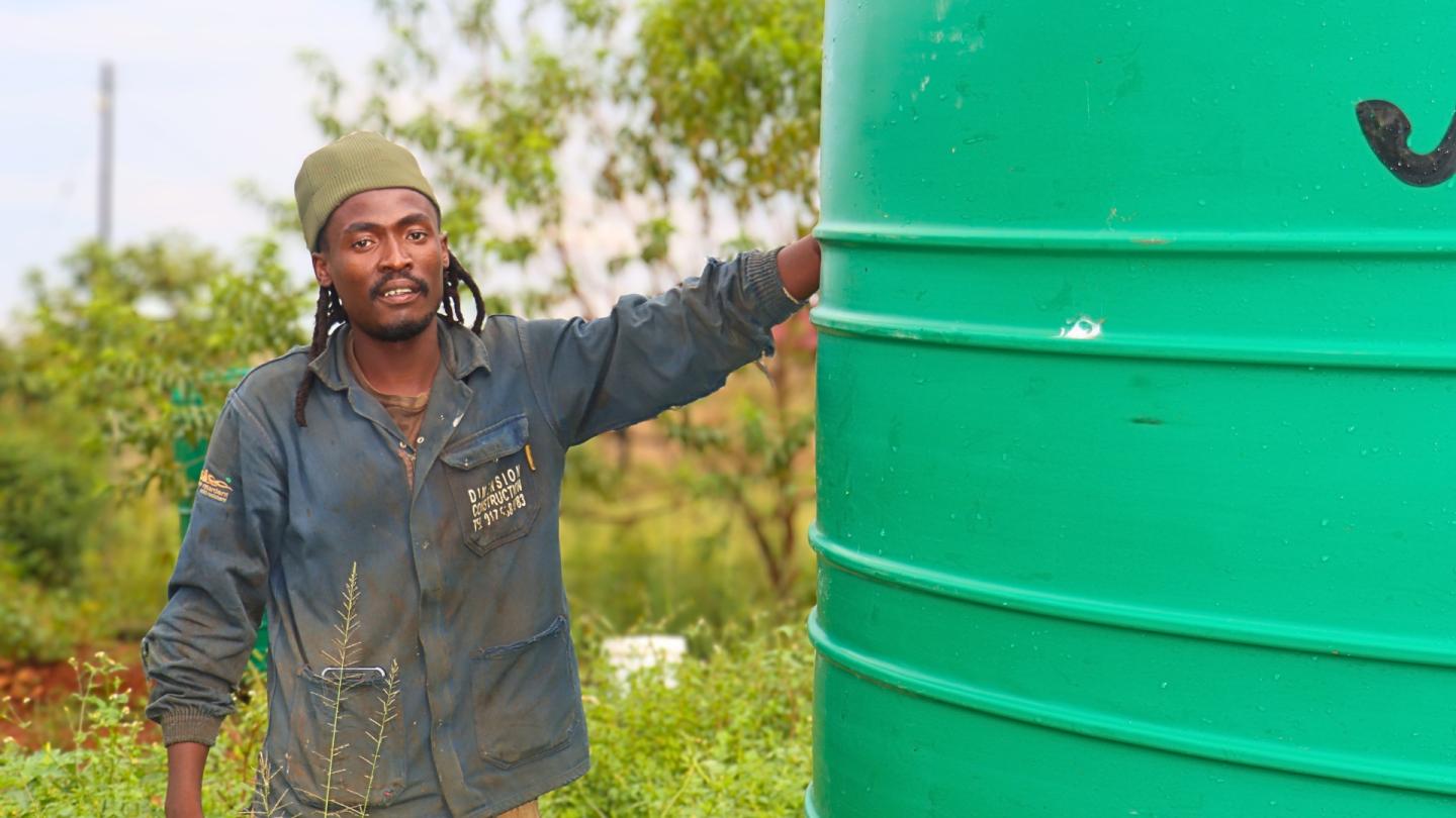 A man standing next to a water tank. 