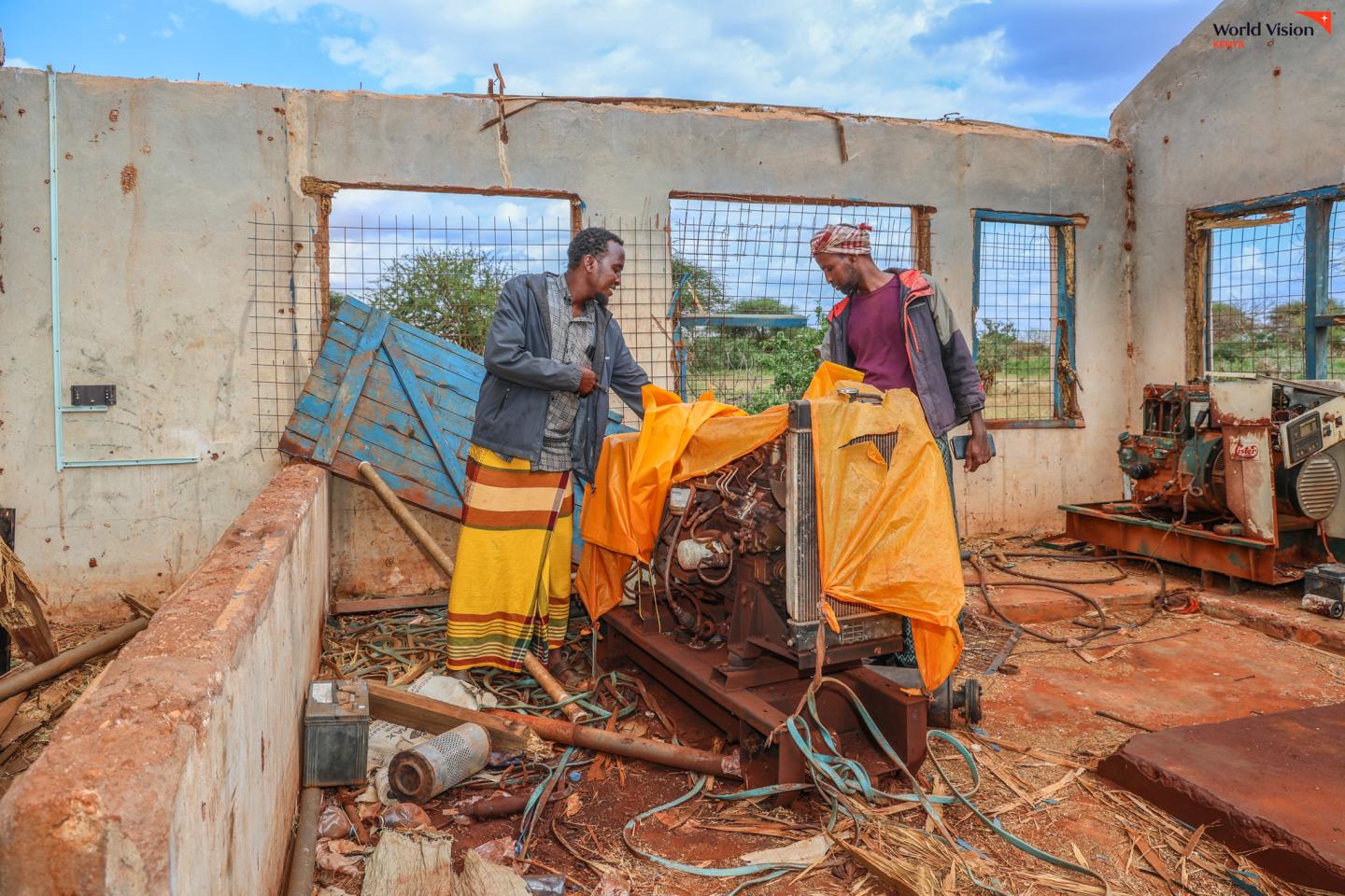 Odow and the borehole operator beside one of the borehole machines that has reduced the borehole’s capacity to provide clean and safe water to the residents of Majabow Village. ©World Vision Photo/Mirriam Kioko