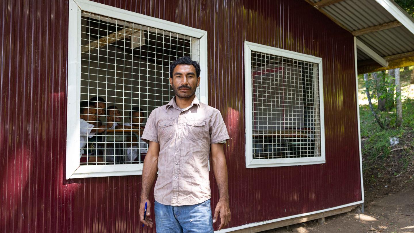 Portrait of Mr. Raka next to a newly renovated classroom building
