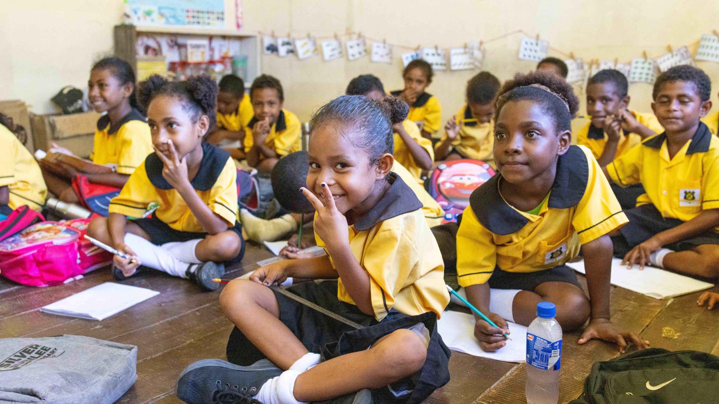 Students at Kupiano Elementary School learning while seated on the floor due to limited classroom