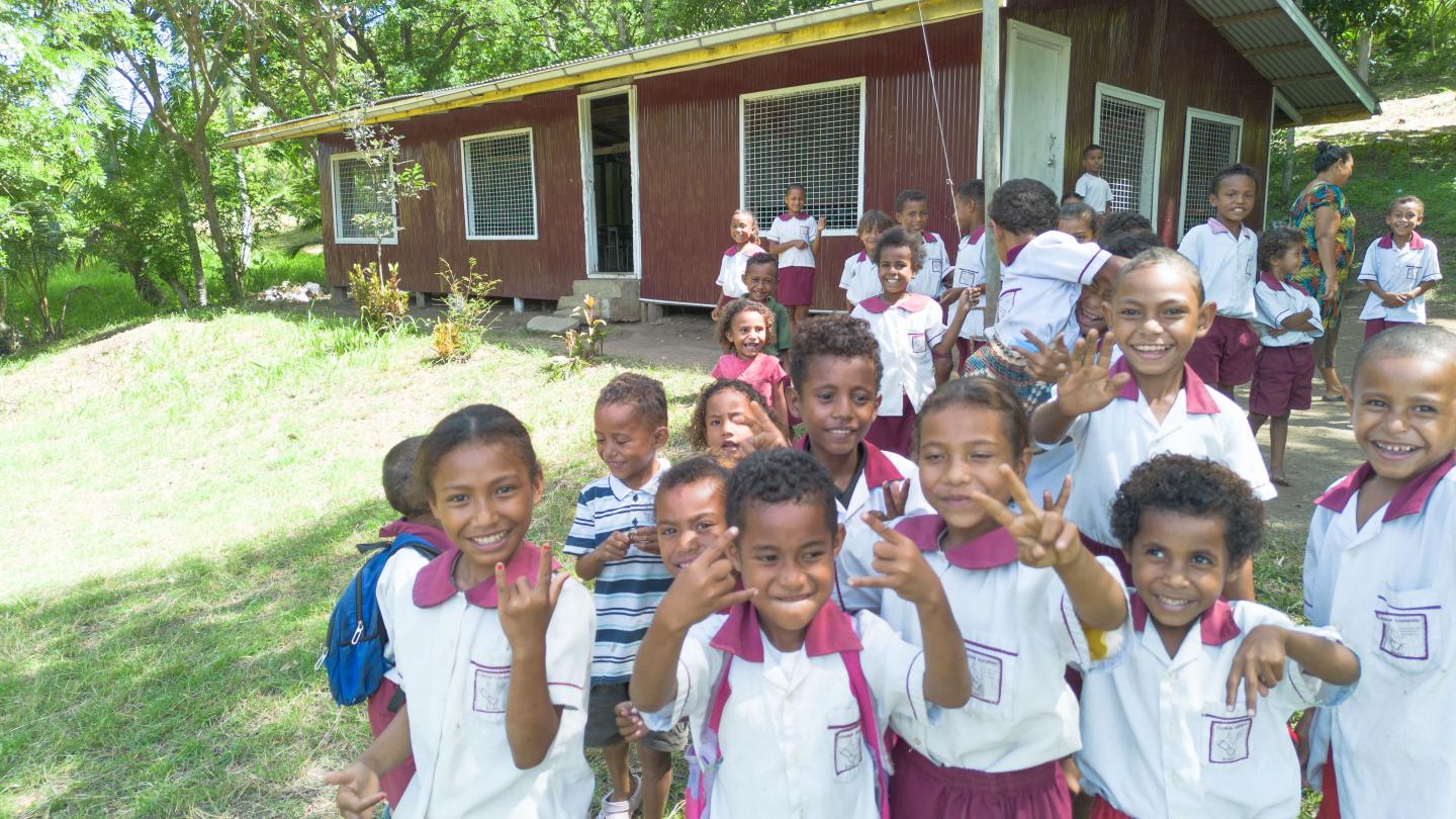 Students smiling and posing proudly in front of their upgraded classroom