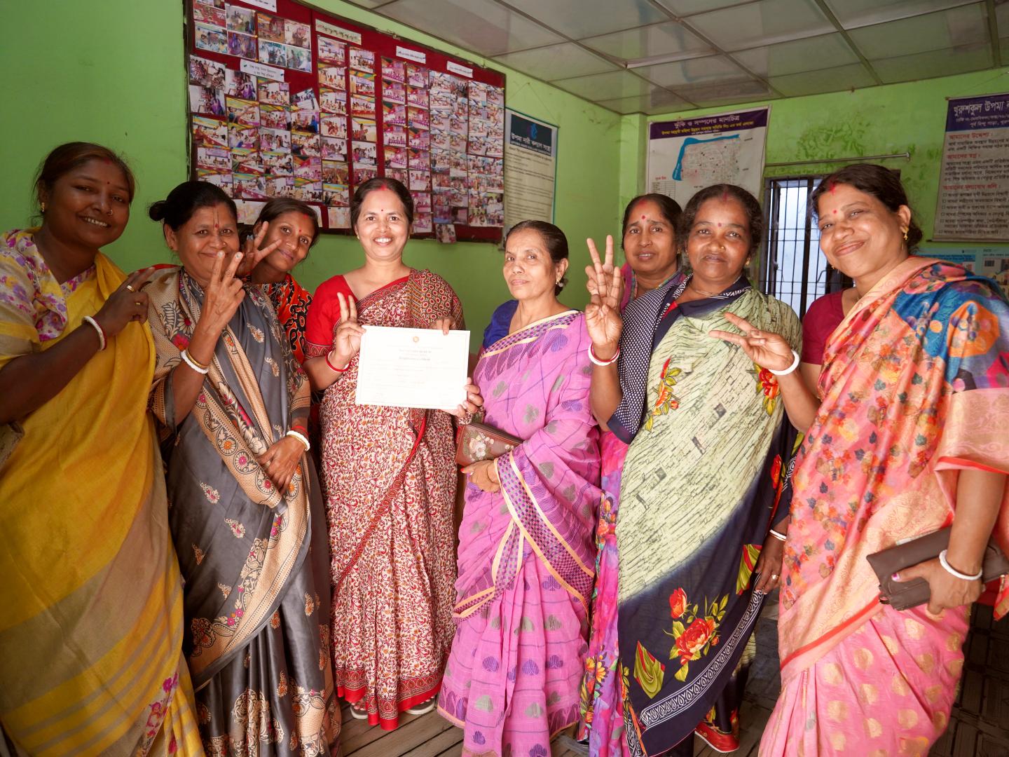 Members of Upoma Nari Kalyan Songstha in Bangladesh hold a certificate inside their community office.