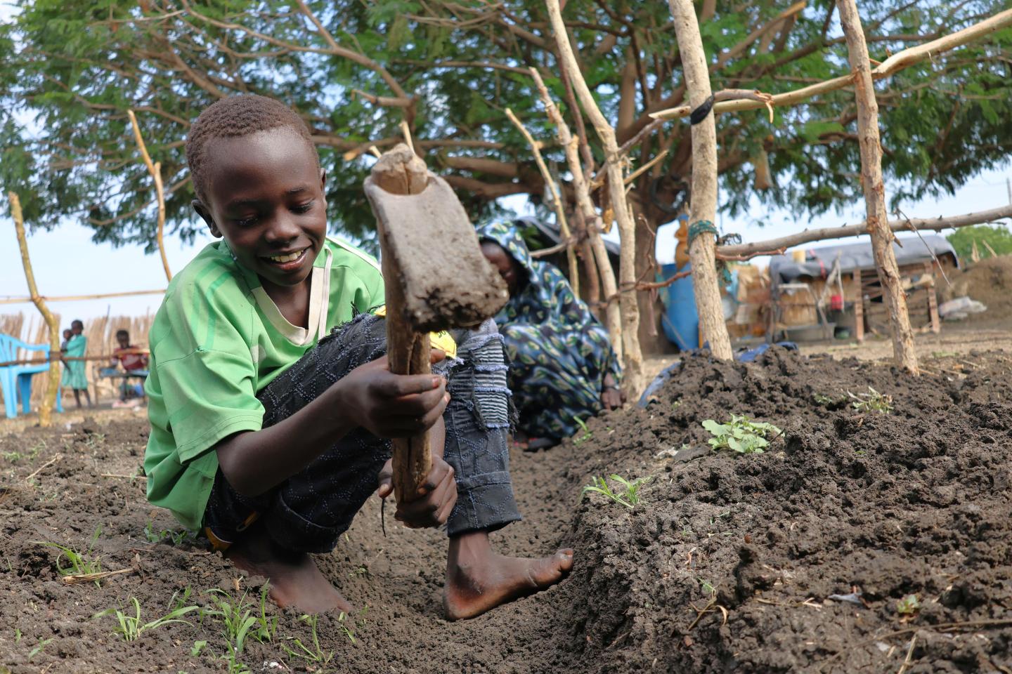 Chol helping his mother dig the water trench 