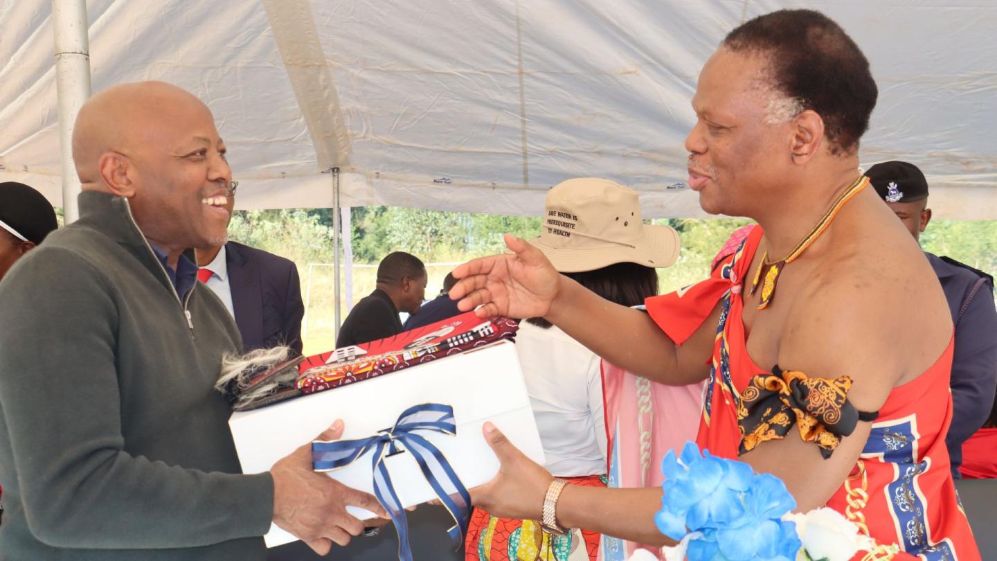 Two people exchanging a gift and shaking hands.