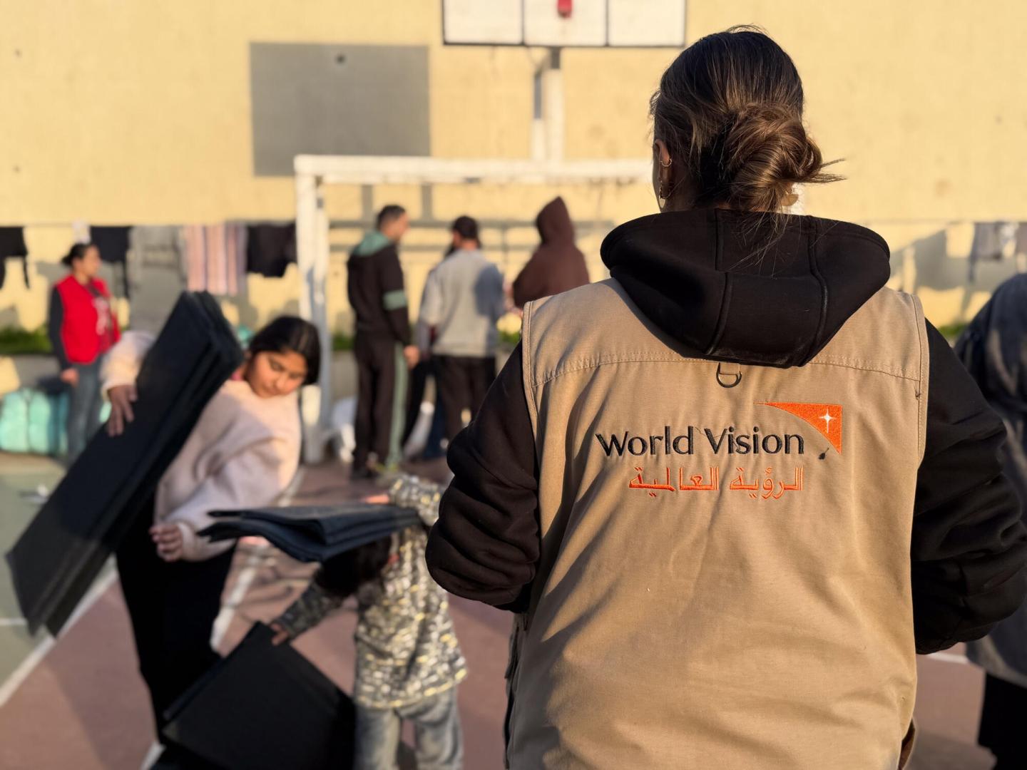 A world vision Lebanon staff stand with her back to the camera at a distrubition