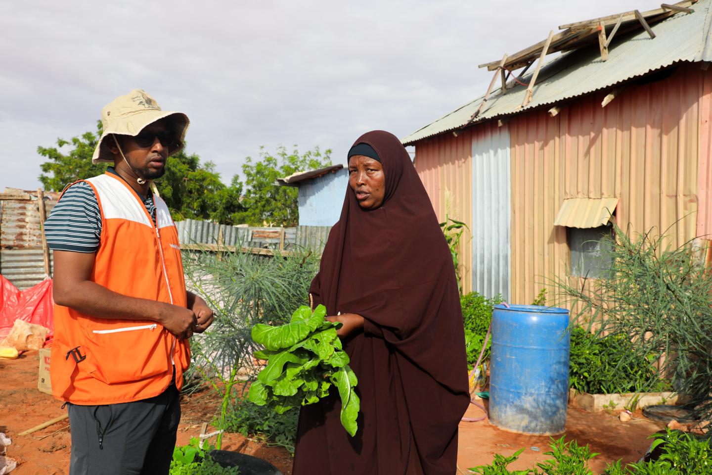 Fatima proudly showcasing her harvest and explaining how her life has improved to World Vision staff.
