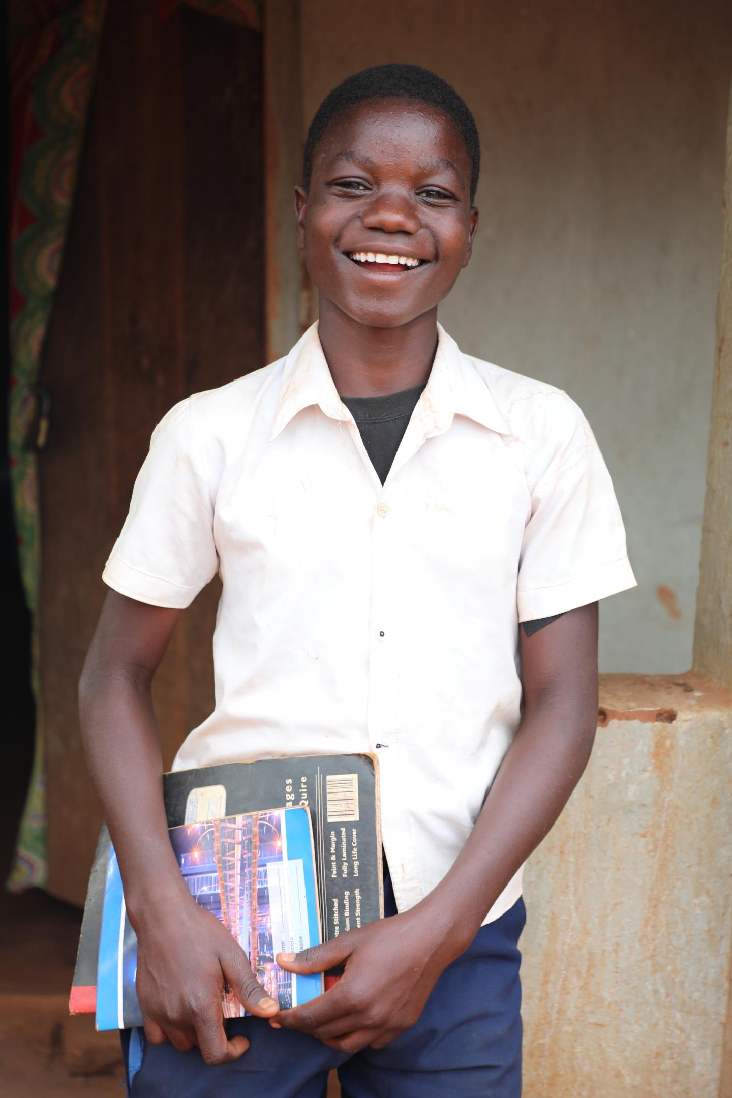 Evanildo proudly holds his books in the school uniform