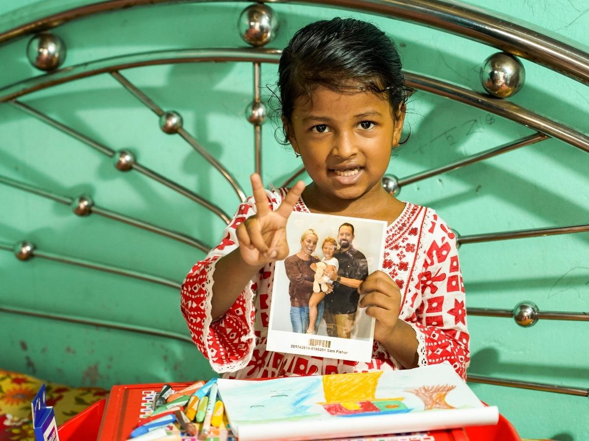 Roja holding a photo of her chosen sponsor family 