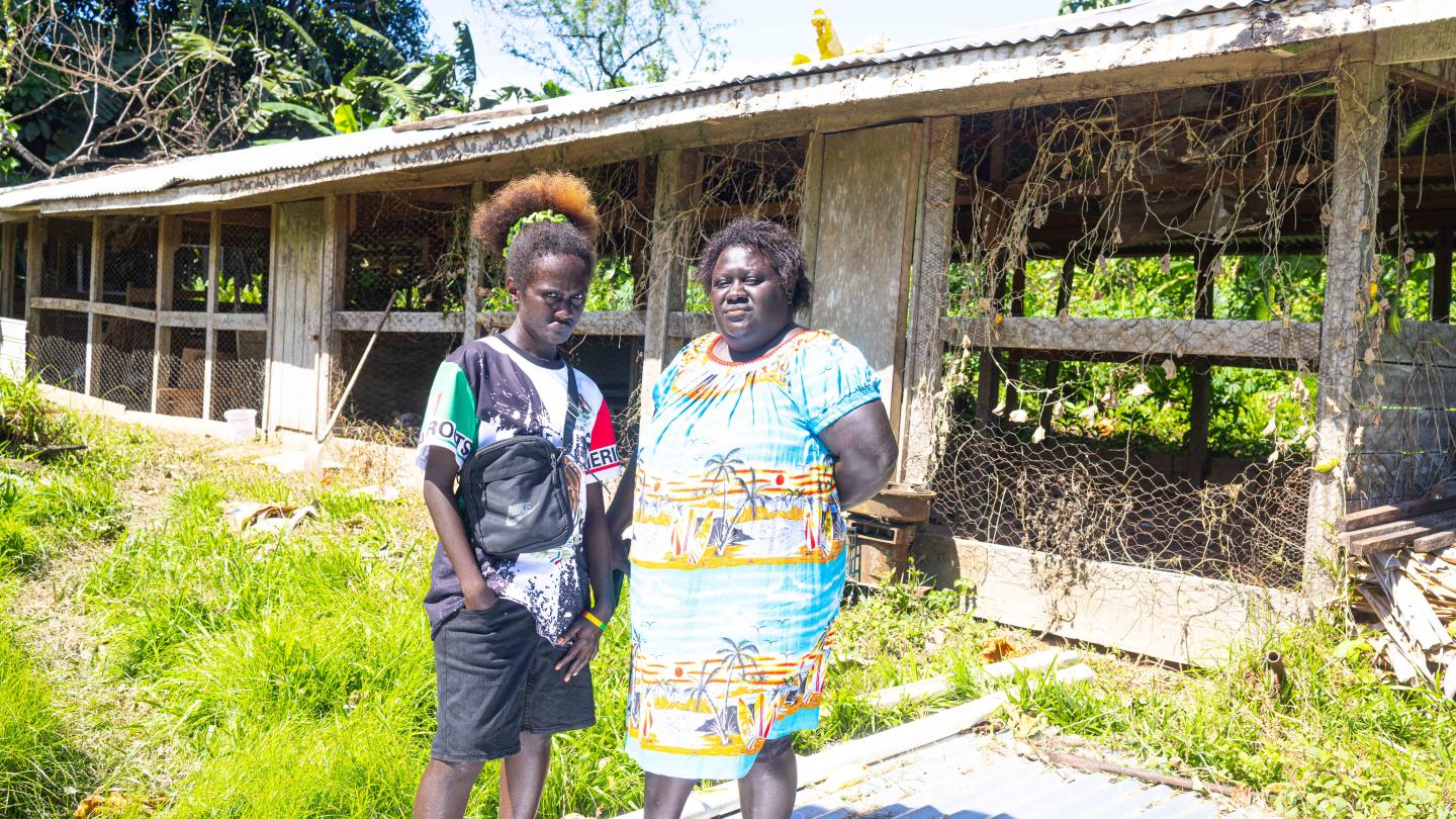Ruthie posing for a photo in front of her poultry with one of her helpers