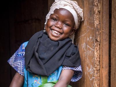 A girl stands against a wall smiling