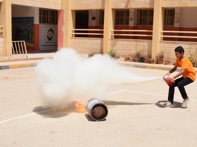 Palestinian Child Learning to use a fire extinguisher during a DRR activity in school