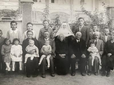Elena's extended family sit for a portrait on her great-grandparents 50th wedding anniversary at the beginning of the war, before the German occupation. Her grandmother is the first adult woman on the left, and her father is on her grandfather's knees beside her.