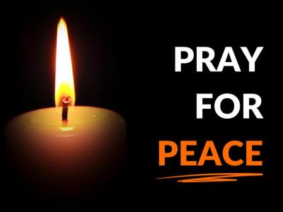 Pray for Peace burning candle against a dark background