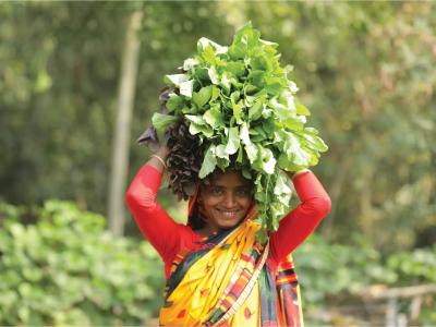 Bangladesh lady carrying greenery on her head 